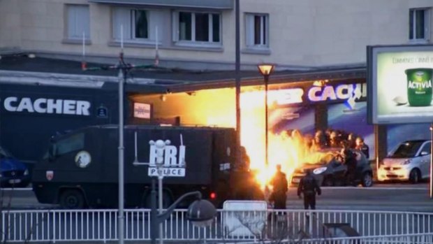 In this image taken from a video provided by PFMTV, police officers storm a kosher grocery to end a hostage situation in Paris. 