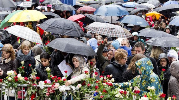People gather beside flower decked railings as they participate in a protest during which the gathering sang a song hated by mass murderer Anders Behring Breivik in Oslo.