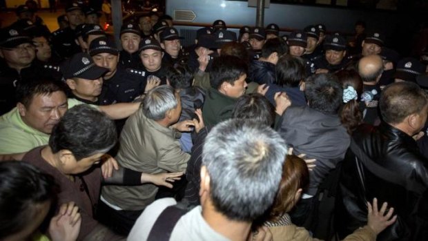 Relatives of passengers onboard Malaysia Airlines flight MH370 push through a police line to march to the Malaysian embassy on Thursday, April 24.