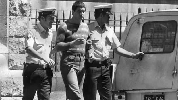 Back in the day: Mark 'Chopper' Read is escorted to a police divvy van.
