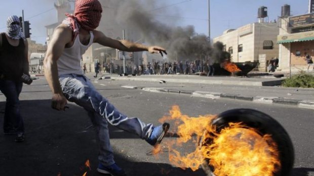 A Palestinian kicks a tyre after setting it ablaze during clashes with Israeli police in Jerusalem. 