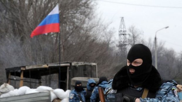 Armed masked men stand at their checkpoint under a Russian flag on a highway that connects the Crimean peninsula to mainland Ukraine.