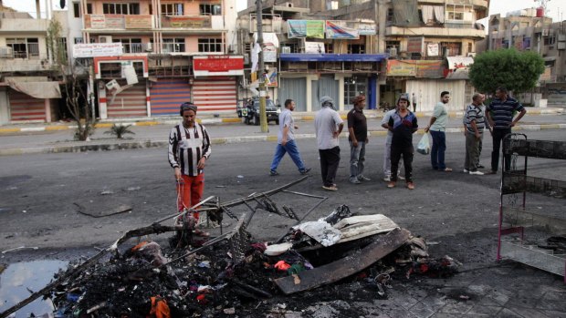 Civilians look at the scene of a car bombing in a neighbourhood of New Baghdad, Iraq.