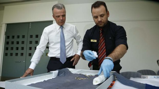 Australian War Memorial director Brendan Nelson watches as Military Heraldry and Technology assistant curator Garth O'Connell unpacks the jersey.