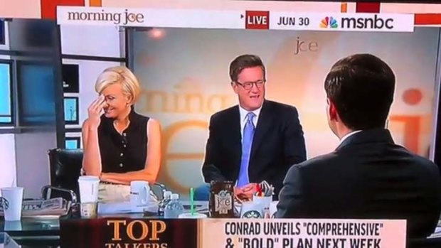 A presenter, left, reacts after Mark Halperin, back to photo, insults Barack Obama.