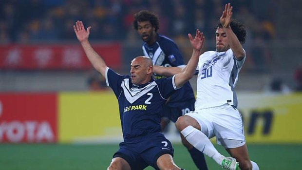 Kevin Muscat comes off second-best while trying to get the better of Olguin Luciano Estebanduring of Tianjin Taida.