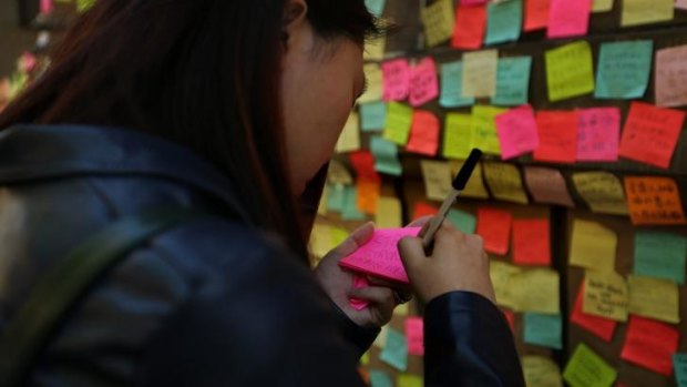 A woman from Hong Kong, whose friends are part of the protest, writes a message of support to post on the wall of Hong Kong House