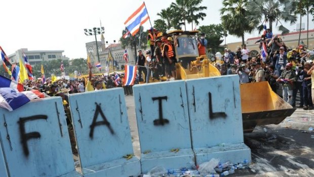 Pressing on: Protesters clear a police barricade near Government House in Bangkok.