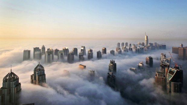 In this Monday, Oct. 5, 2015 photo, a thick blanket of early morning fog partially shrouds the skyscrapers of the Marina and Jumeirah Lake Towers districts of Dubai, United Arab Emirates. Dubai?s rapid transformation from a desert outpost into one of the world?s most architecturally stunning cities is mapped out in the Marina. Where just 15 years ago there was empty, flat land, today a bustling neighborhood thrives centered around a canal and an impressive skyline that pierces through the clouds. (AP Photo/Kamran Jebreili)
