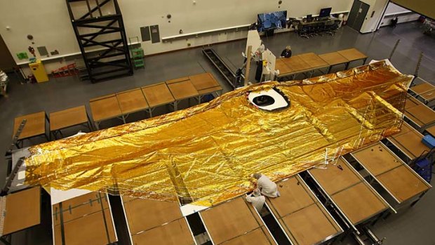 Technicians work on folding membranes of a full scale test article five-layer sun shield, made of uncoated kapton, that will shield the James Webb Space Telescope from the sun and heat.