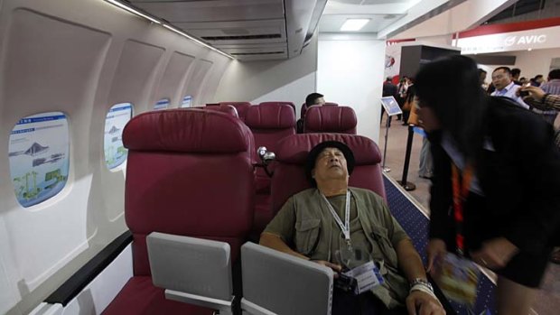 A visitor tries a business class seat in a passenger cabin model of the C919.