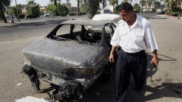 An Iraqi traffic policeman inspects a car destroyed by the Blackwater guards in 2007.
