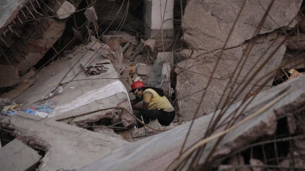A rescue worker searches the rubble of the collapsed building.