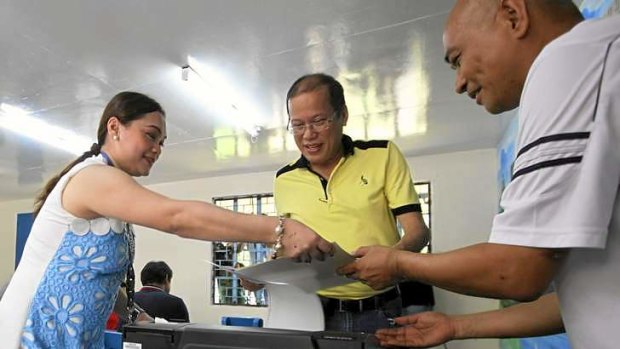 President Benigno Aquino hands his ballot to election workers during midterm elections in his hometown in Hacienda Luisita, in the northern Philippines.
