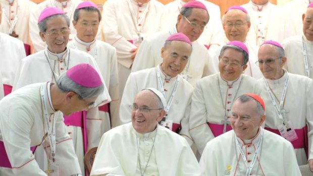 Pope Francis laughs with bishops as he signs the guestbook during a meeting with the bishops of Korea at the headquarters of the Korean Episcopal Conference in Seoul, South Korea. 