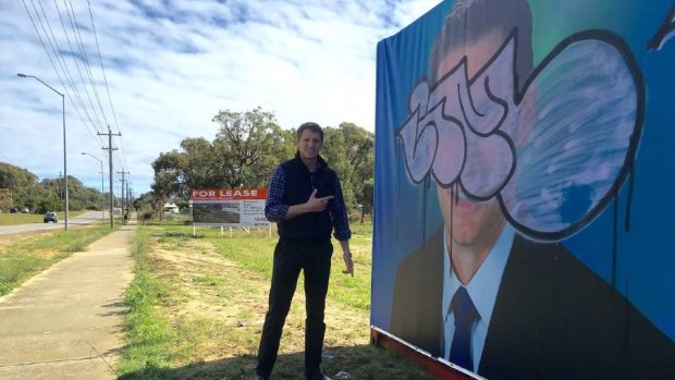 Canning MP Andrew Hastie with the campaign poster that copped a spray from a vandal. 