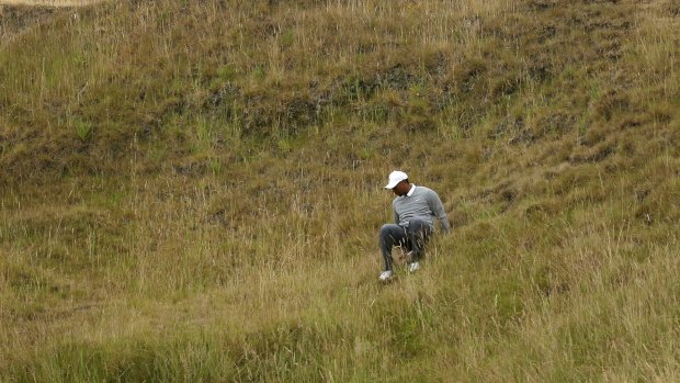 Tiger Woods slips in the tall fescue grass on the 10th hole of the US Open. He posted an 80 in the opening round.