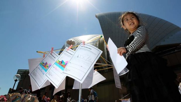 Celebration for all: Four-year-old hangs her drawing of the opera house on a clothes line.