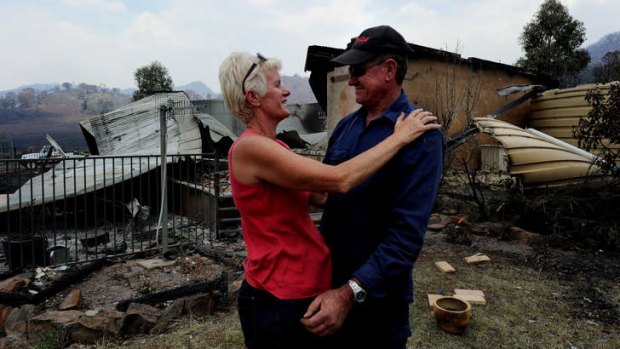 We're still here &#8230; Dawn Keirle and her neighbour Perry Wilkinson in front of the remains of Ms Keirle's home in Coonabarabran.