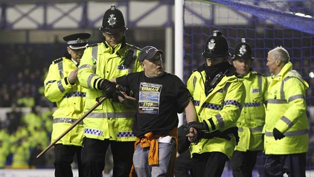 Protest ...  the man is taken away after handcuffing himself to the goalpost