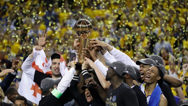 Golden State Warriors players, coaches and owners hold up the Larry O'Brien NBA Championship Trophy after game 5 of basketball's NBA finals between the Warriors and the Cleveland Cavaliers in Oakland, California.