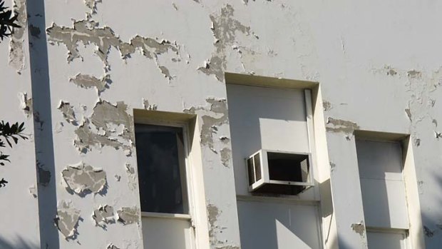 Paint peels off the outside walls of the Waltons building.