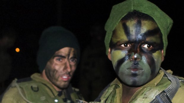 Israeli soldiers wearing camouflage paint wait for orders to begin the move into Gaza.
