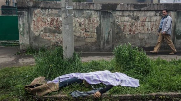 The body of a man killed in the clash between Ukraine and pro-Russian forces lies along the street near a police station that was attacked and burned in Mariupol.