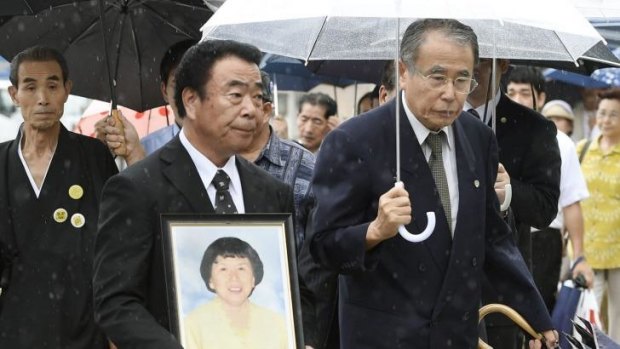 Mikio Watanabe, holding a portrait of his late wife Hamako, at the Fukushima District Court.