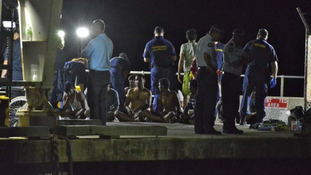 Customs officials and rescue personnel watch over survivors of the capsized boat at Christmas Island docks on Tuesday night.