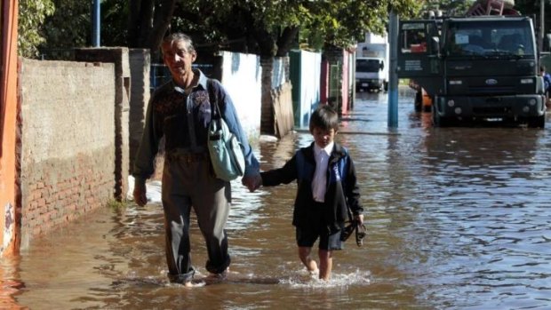 Deep trouble: A man and his grandson walk through floodwaters near the Paraguay River in Asuncion, Paraguay.  Brazil's southern state of Parana has been hit by heavy floods.