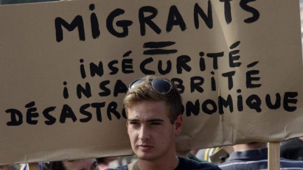 Far-right: A man holds a banner at a protest in Calais on Sunday that reads "Migrants equal insecurity, unhealthiness and economic disaster".