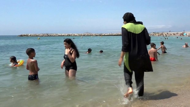 A woman gets into the sea wearing a burkini, a wetsuit-like garment that also covers the head, in Marseille, France. 