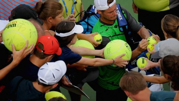 Lleyton Hewitt of Australia autographs tennis balls for fans after downing Jurgen Melzer.