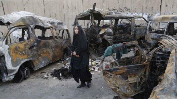 Charred wrecks: A woman walks among vehicles destroyed in a car bomb attack in Baghdad.