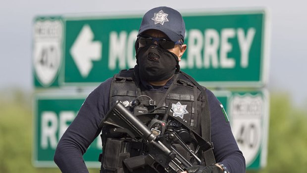 A federal policeman guards the area where dozens of bodies, some of them mutilated, were found on a highway.