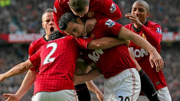 Robin van Persie of Manchester United is mobbed by his team-mates after scoring the opening goal against his former club Arsenal.