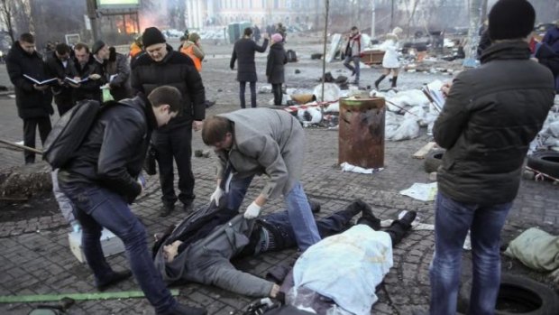 Grim toll ... Forensic experts and police look at dead bodies lying on the ground after clashes between anti-government protesters and security officers, in central Kiev.