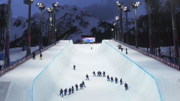 Volunteers inspect the condition of the halfpipe before competitors commence practice sessions.