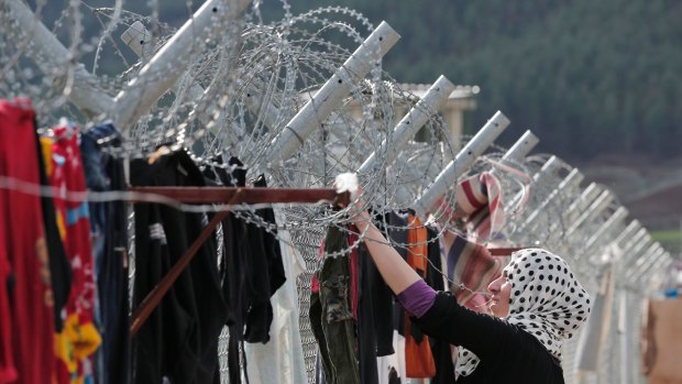 A Syrian refugee hangs clothes to dry on a barbed-wire fence at a refugee camp in Islahiye, Turkey.