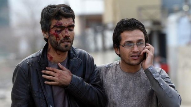 An Afghan man who was injured during an attack on a guesthouse by Taliban gunmen on March 29,  2014 leaves the scene of the attack in Kabul.