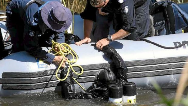 A police diver hands over an object found in the Yarra River in relation to the disappearance of Milorad Dapcevic.