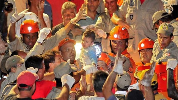 Where there's life ... firefighters hold Nicolas Barreto, who survived 15 hours trapped in a buried house.