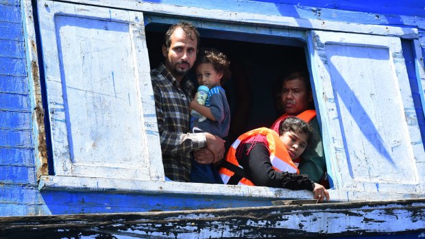 Haidar 41 (left) from Baghdad in Iraq holding his son Mohamed, three (2nd from left) with Nasma 25 (right) Libyan of Bangladeshi descent with her husband as they wait to be rescued from their wooden boat by the Migrant Offshore Aid Station crew supported by Medecins Sans Frontieres last Wednesday.