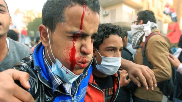 An injured Egyptian protester ... is helped away during clashes.