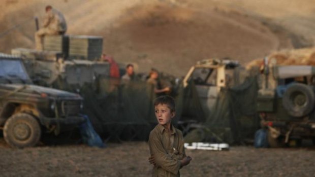 Body of work: An boy looks on as German ISAF soldiers prepare a temporary camp to overnight in during a long term patrol east of Kunduz, Afghanistan.
