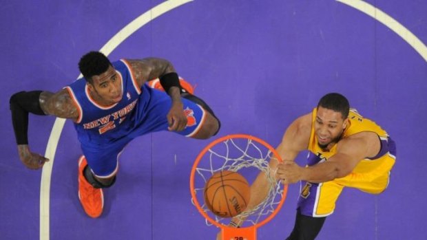Los Angeles Lakers forward Xavier Henry dunks as New York Knicks guard Iman Shumpert defends.