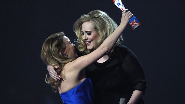 Adele accepts one of her awards from Kylie Minogue.