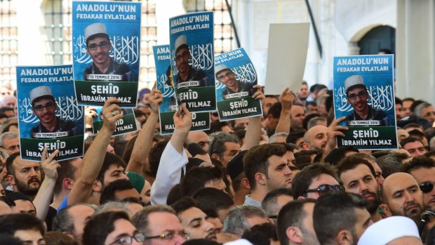 People hold the pictures of the victims of the thwarted coup at Fatih mosque in Istanbul, Turkey..