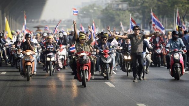 Anti-government protesters with Thai national flags ride their motorbikes as they rally on a main road in Bangkok 